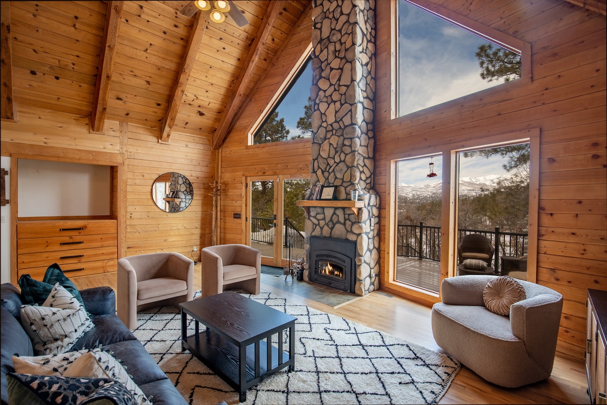Living room with a stone fireplace, vaulted ceiling, and mountain views through picture windows at Wildcat Cabin, Durango