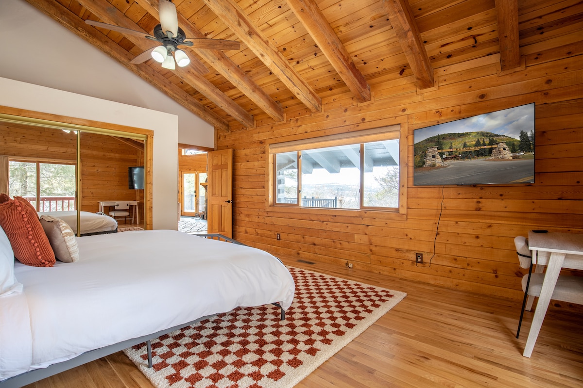 King bedroom with mountain views and a checkered rug at Wildcat Cabin